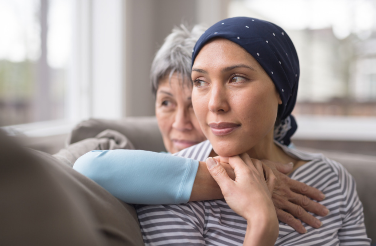 Two women hugging, older and younger woman sitting on couch