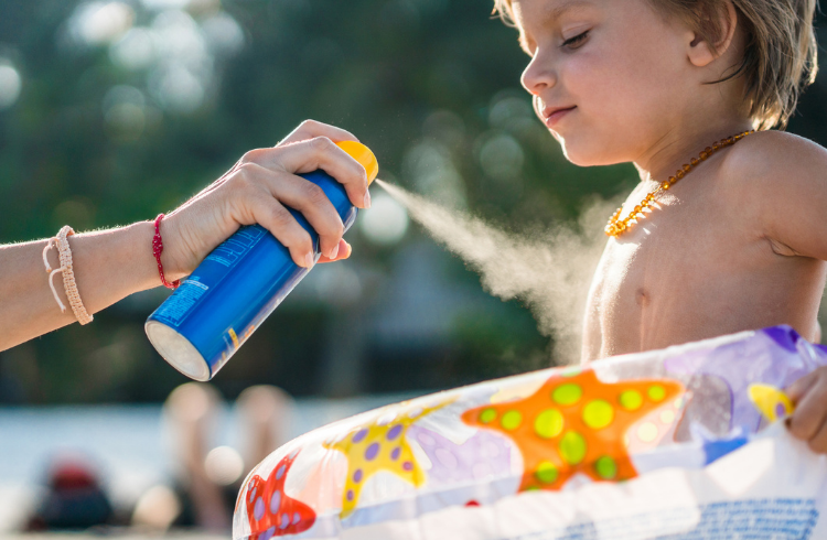 Sprays sunscreen on boy