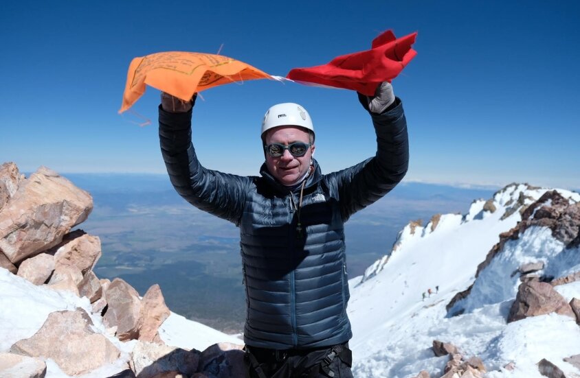 Steve Clossick with prayer flags on summit of Mt Shasta_Climb Against the Odds 2018