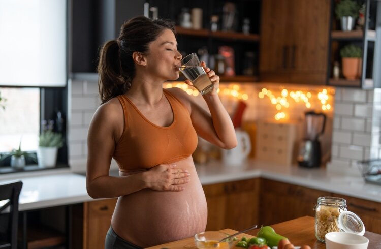 Pregnant woman drinks glass of water 