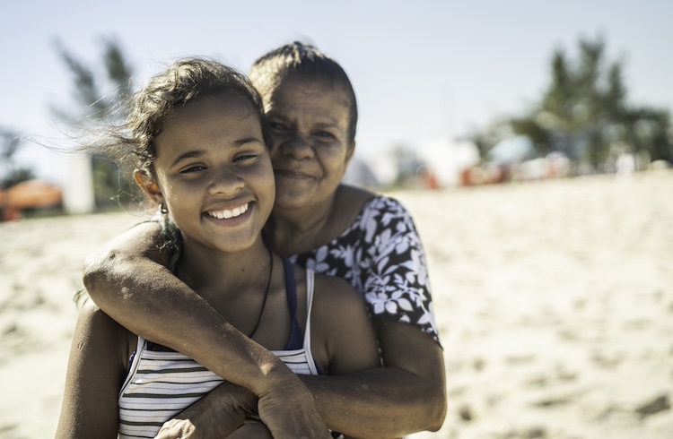 Portrait of grandmother and granddaughter embracing in the beach