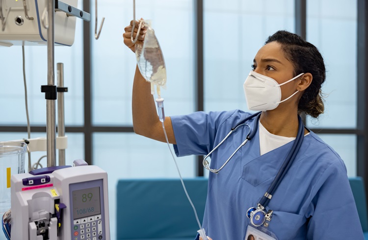 Nurse holds IV bag with tubing connected to a medical device