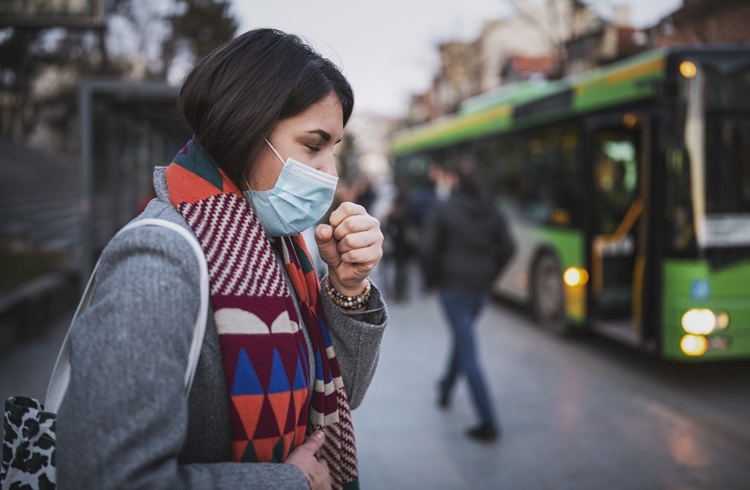 woman wearing a mask coughs in air pollution from traffic